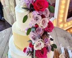 Pink and purple floral cascading down a three tier wedding cake | Petite Sweets by Laura
