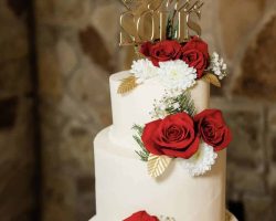 White wedding cake adorned with red roses and gold topper | Petite Sweets by Laura